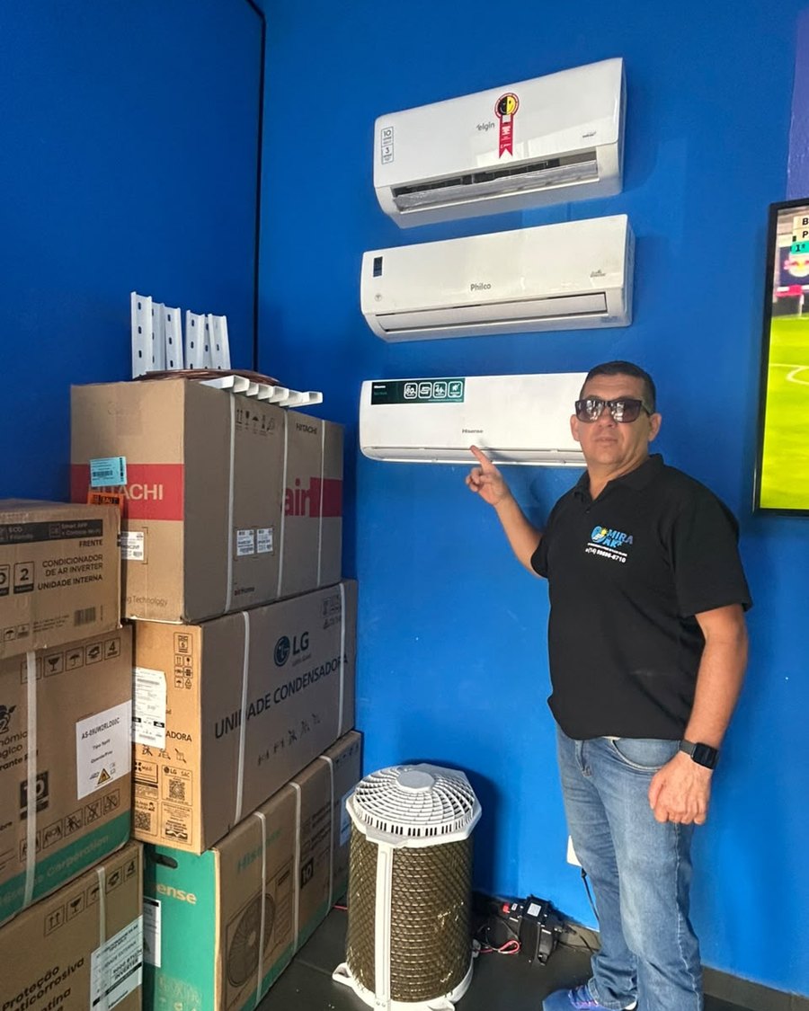Giba, fundador da Mira Ar, ao lado de aparelhos de ar-condicionado instalados na parede